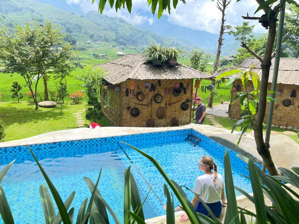 a woman walking by a swimming pool next to a house at Sapa Bamboo Eco in Sapa
