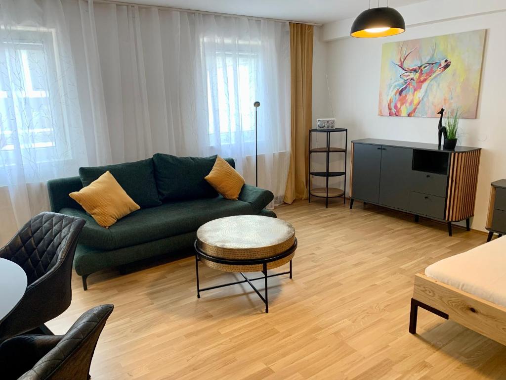 uma sala de estar com um sofá verde e uma mesa em Ruhiges Apartment mit Terrasse im Zentrum St. Pölten em Sankt Pölten