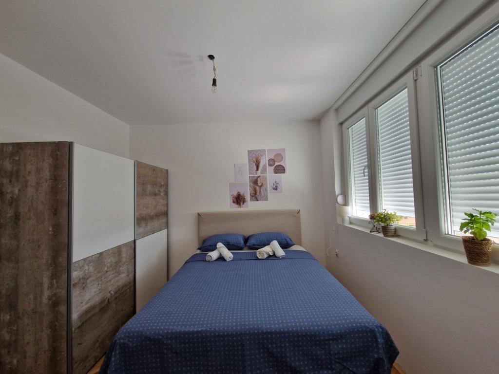 a bedroom with a bed with blue sheets and windows at Apartman REA 1 in Pirot