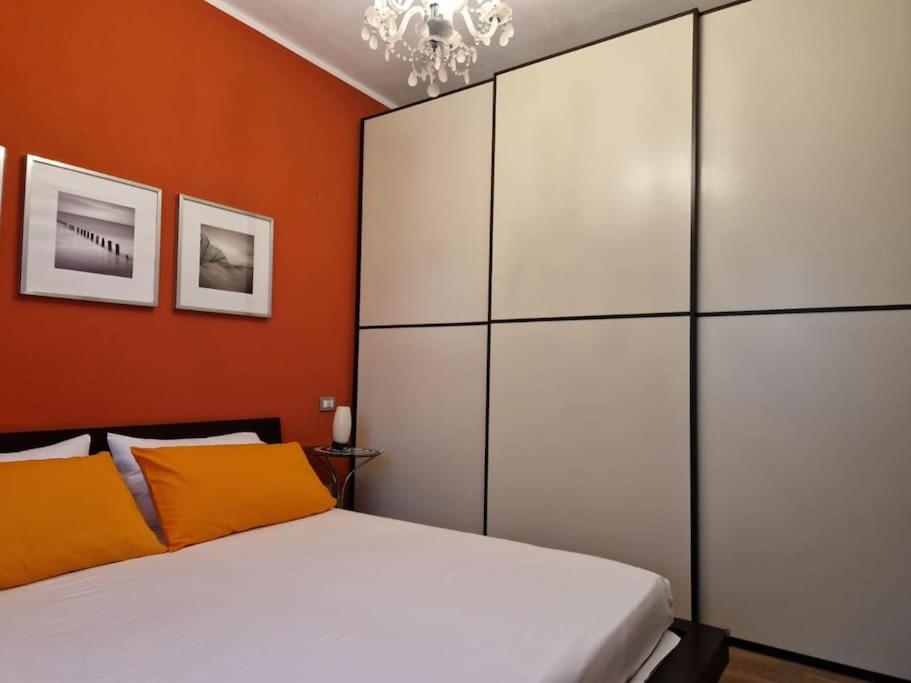 1 dormitorio con cama blanca y pared de color naranja en Mysa Properties -Luminoso bilocale, Cormano, en Cormano