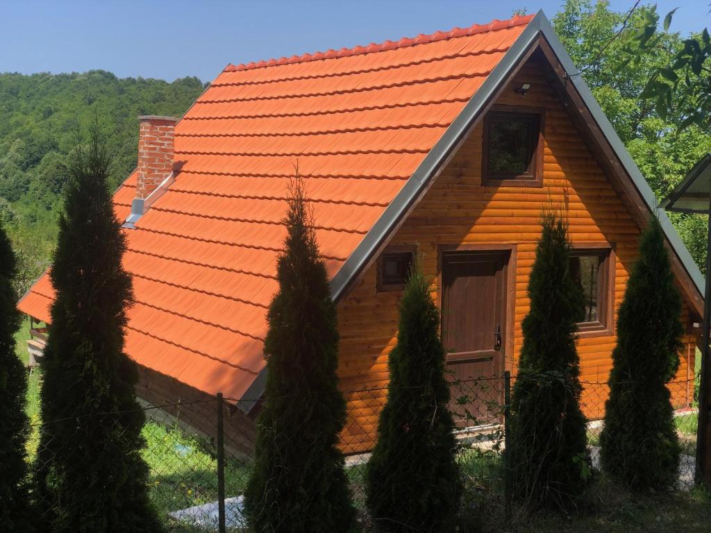 Lepterija的住宿－Koliba Joca，一座拥有橙色屋顶和一些树木的房子