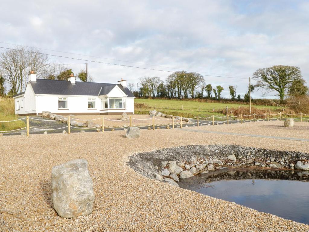 une maison avec un rocher et un étang en face de celle-ci dans l'établissement The Water's Edge, à Cavetown