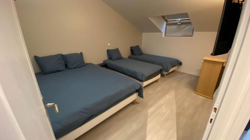 a room with two beds with blue sheets and a television at Appartement Cosy in Le Bourget