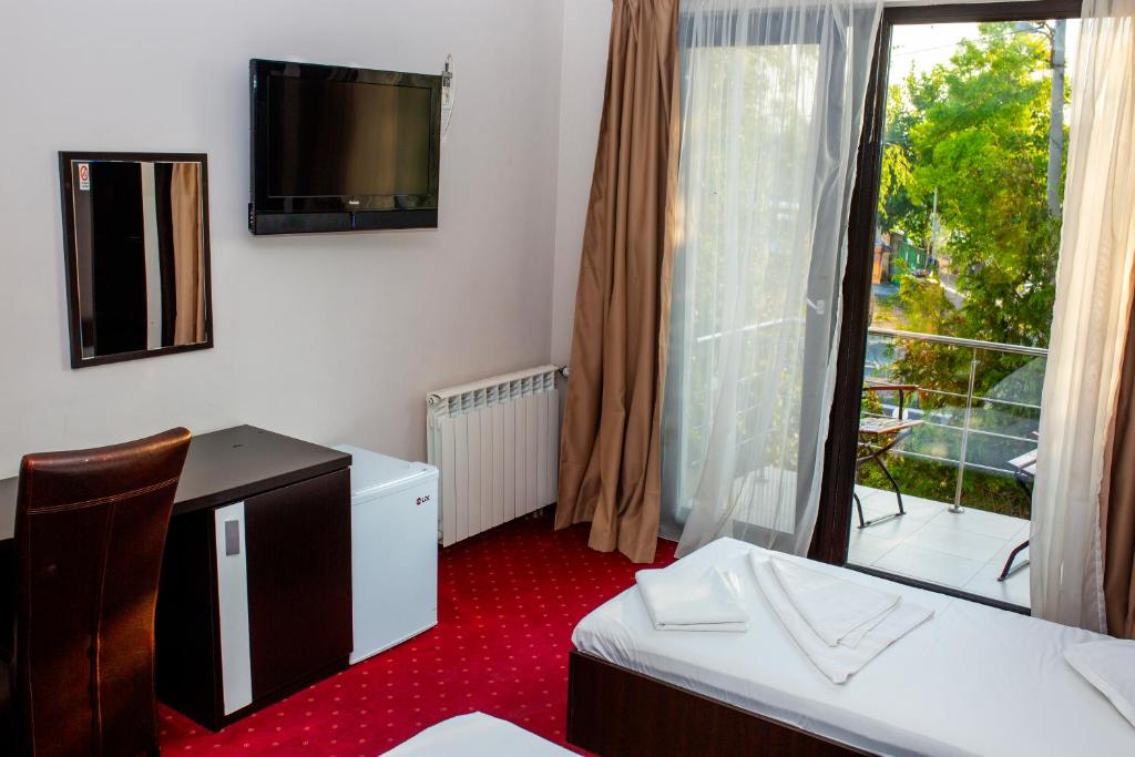 een kamer met een televisie, een raam en rode tapijt bij Vila La Mer in Eforie Nord