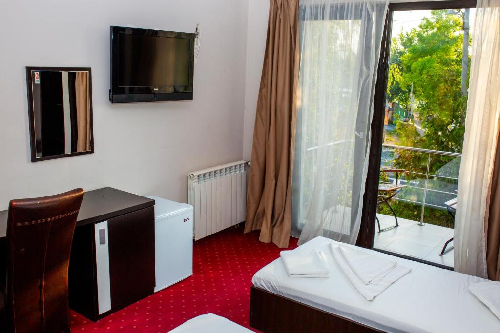 Habitación con TV, ventana y alfombra roja. en Vila La Mer, en Eforie Nord