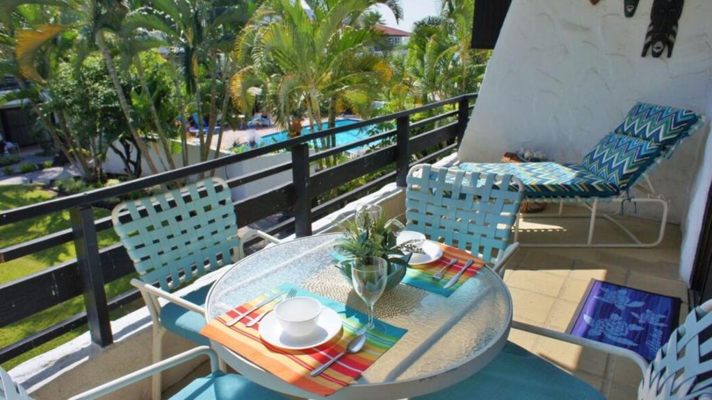 Una mesa y sillas en un balcón con vista a una piscina. en Casa de Emdeko 225, en Kailua-Kona