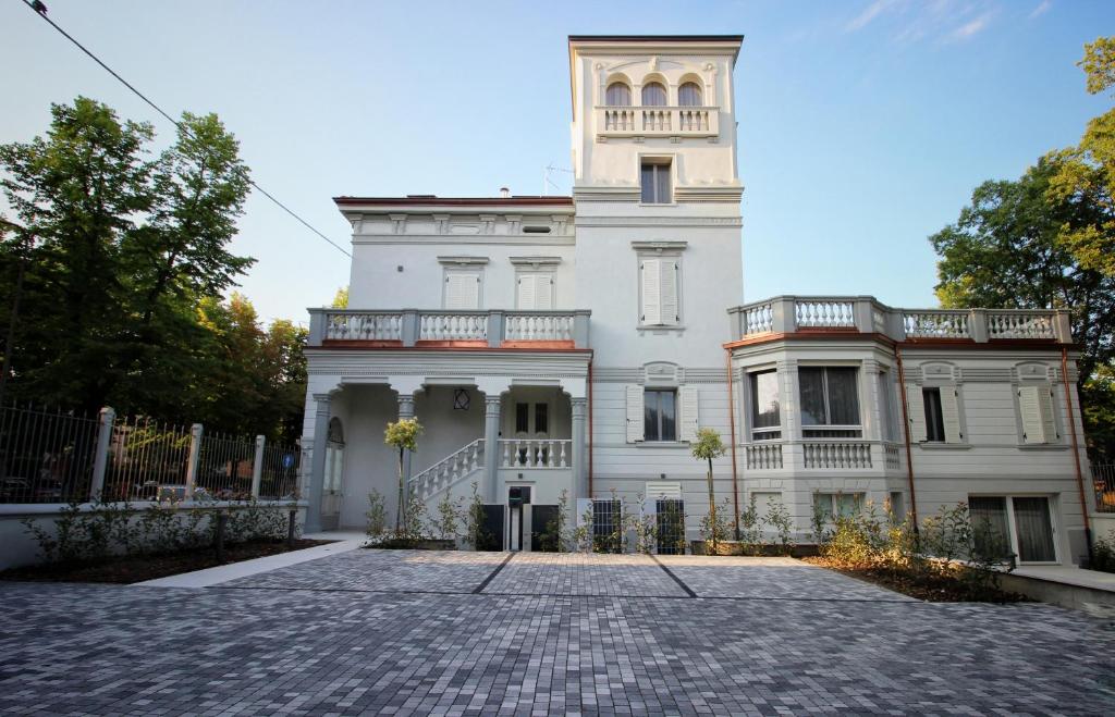 uma grande casa branca com uma cerca em frente em Villa Benatti em Carpi