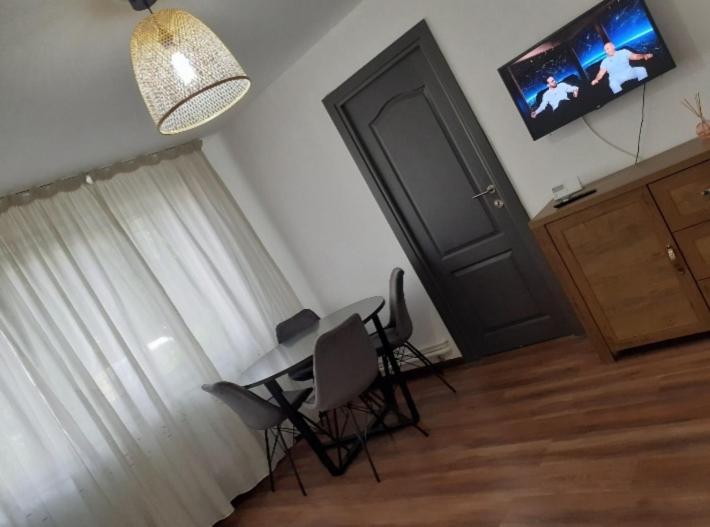 a room with a table and chairs and a television at Silene Studio in Craiova