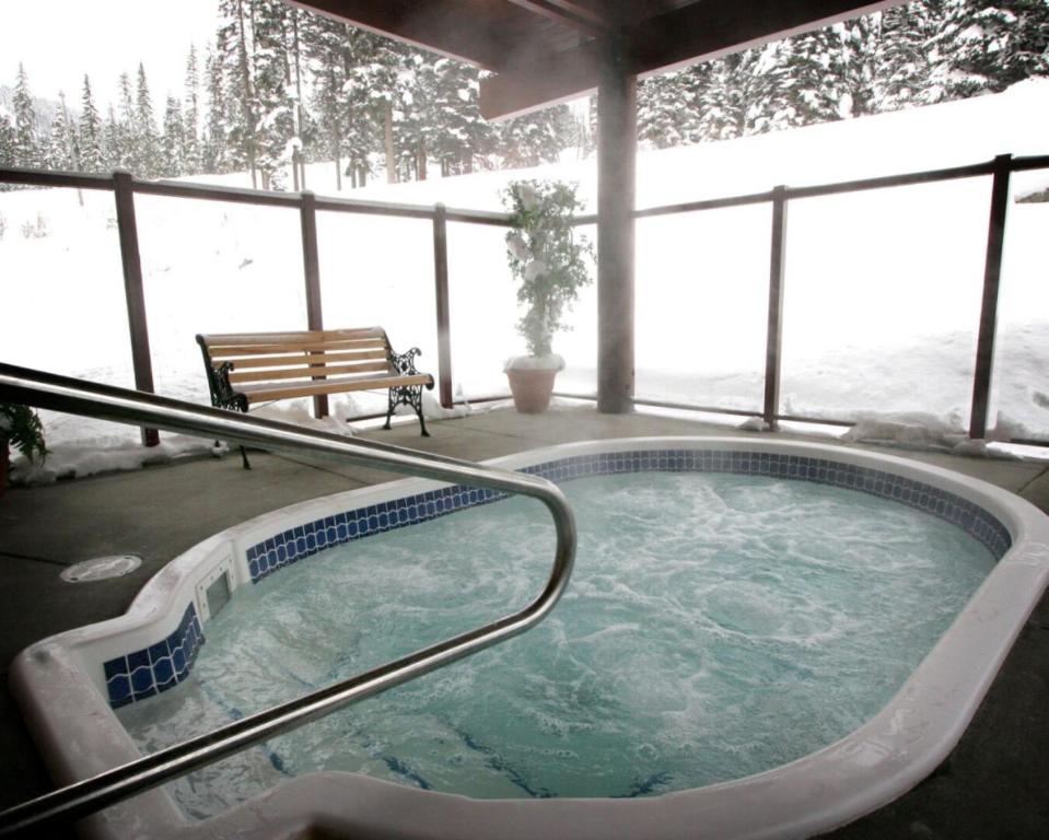 eine Whirlpool-Badewanne mit einer Bank im Schnee in der Unterkunft Cahilty Hotel & Suites in Sun Peaks