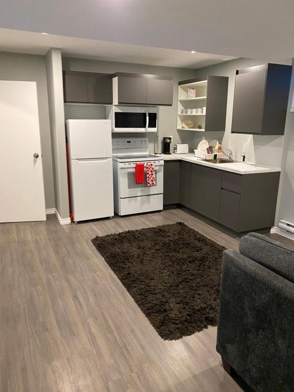 a kitchen with white appliances and a couch at 1 Bedroom Modern Secondary Suite in Saskatoon