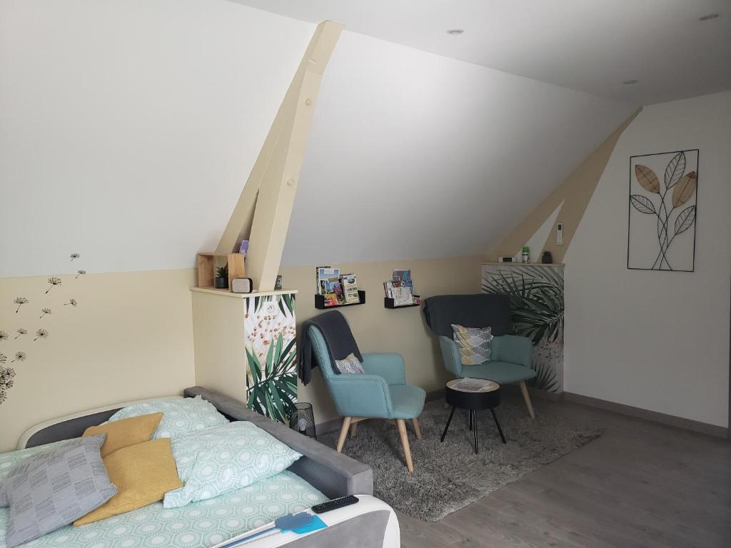 una camera da letto con letto e sedie in mansarda di Le charmillon, Appartement cosi avec double garage a Mancey