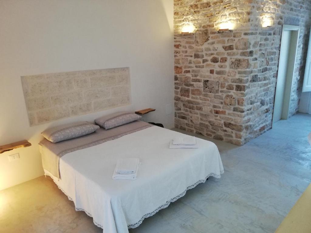 een slaapkamer met een bed met een bakstenen muur bij Holiday Home Trullo Antico in Ostuni