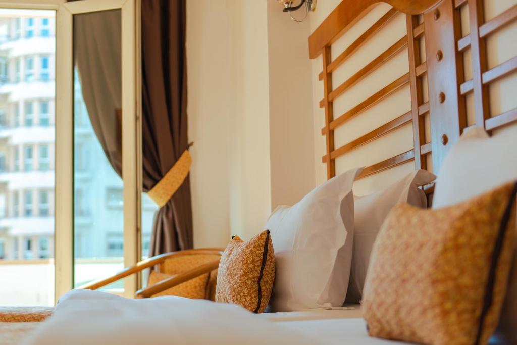 1 dormitorio con cama con almohadas y ventana en Hôtel Rembrandt en Tánger
