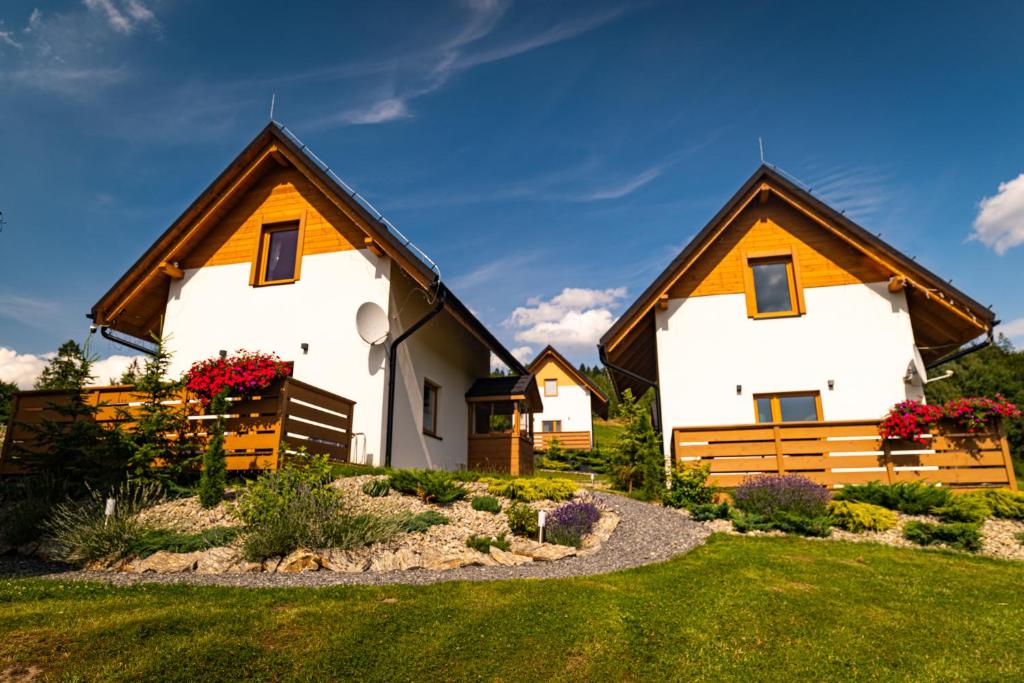 dom z dwoma białymi domami i ogródkiem w obiekcie Domki do Wynajęcia "Osadowe Wzgórze" w Wiśle w Wiśle