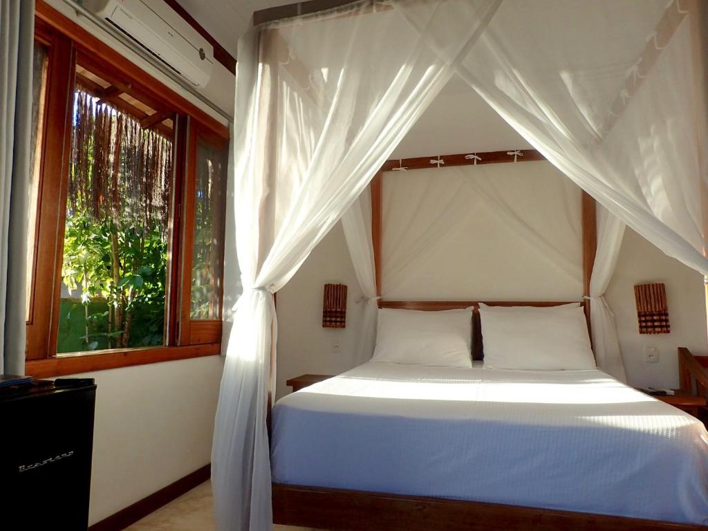 a bedroom with a white bed with a canopy at Luar do Leão Bungalow in Barra Grande
