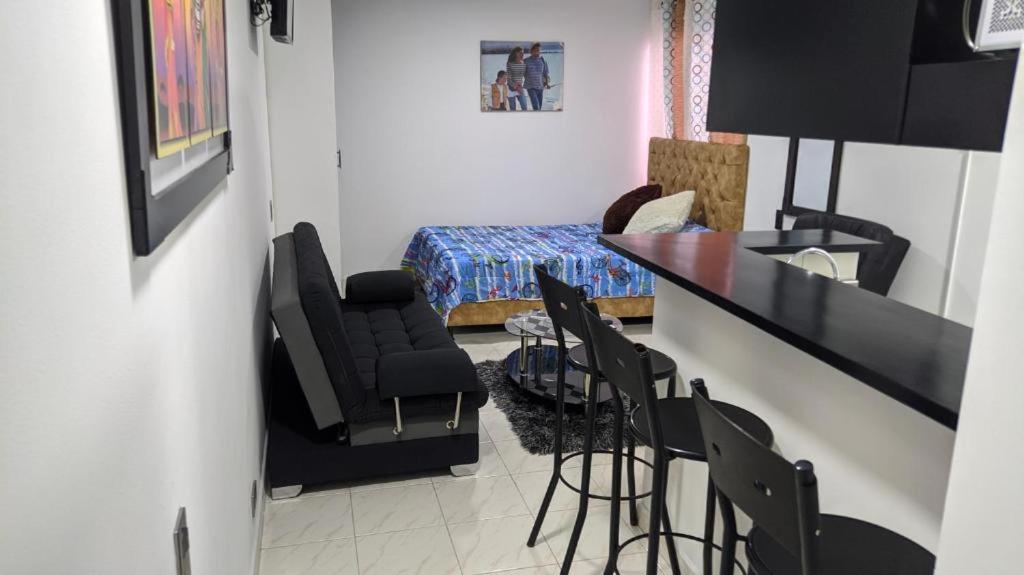 1 dormitorio y sala de estar con bar y sillas. en Apartaestudio Centro De Pereira, en Pereira