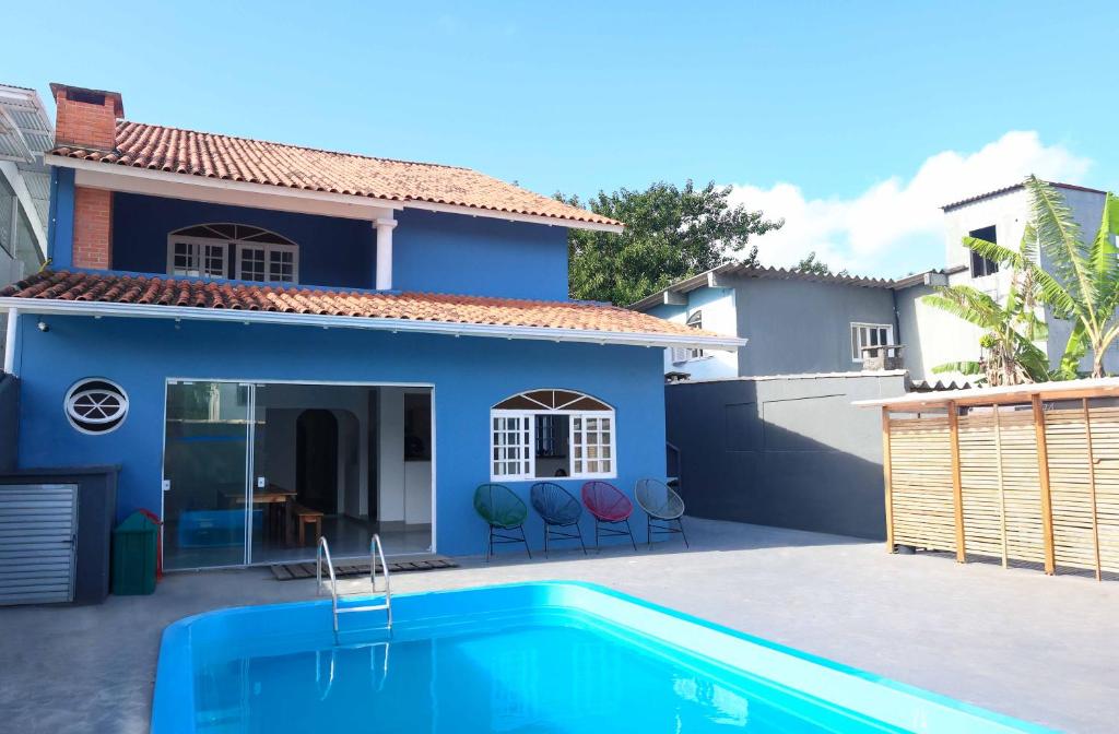 une maison bleue avec une piscine en face de celle-ci dans l'établissement Sea Wolf Hostel - Lagoa da Conceição, à Florianópolis