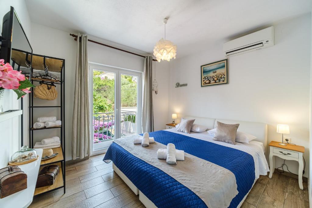 a bedroom with a blue and white bed and a window at Rooms Anna in Milna