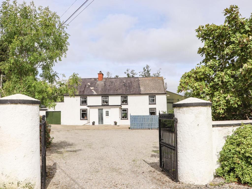 a white house with a gate in front of it at An Grianan in Ballynabola