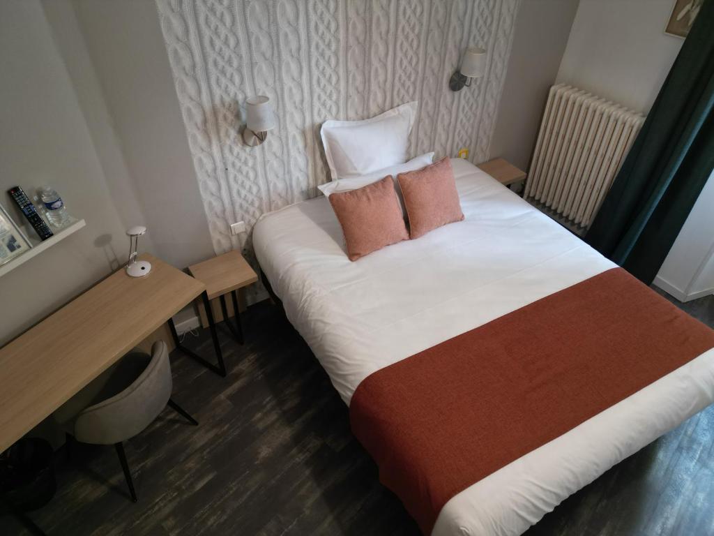 a hotel room with a bed and a desk at Hôtel les Platanes in Villeneuve-sur-Lot