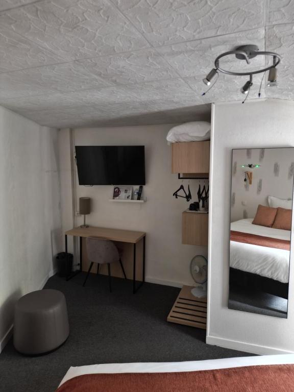 a bedroom with a bed and a desk and a tv at Hôtel les Platanes in Villeneuve-sur-Lot