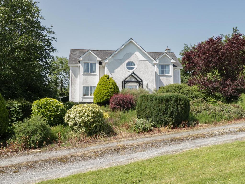 ein Haus auf einer unbefestigten Straße mit Büschen in der Unterkunft The White House in Drumshanbo