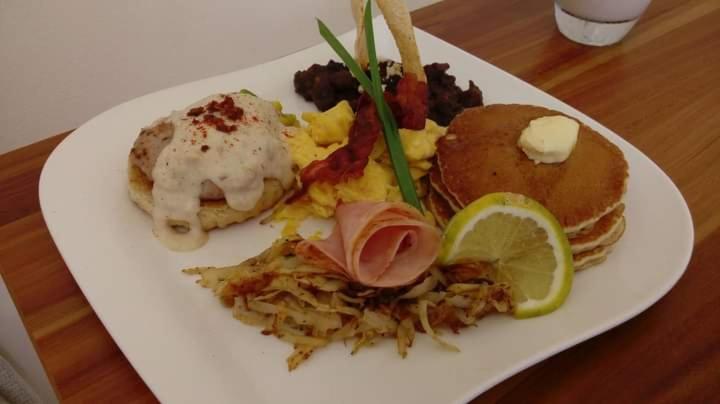a plate of breakfast food on a wooden table at Hotel Posada Edem in Cozumel