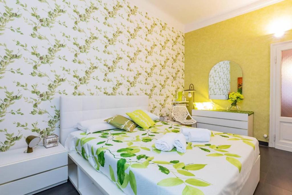um quarto com uma cama branca com folhas verdes na parede em [IHost Apartment] - Bassini 46 em Milão