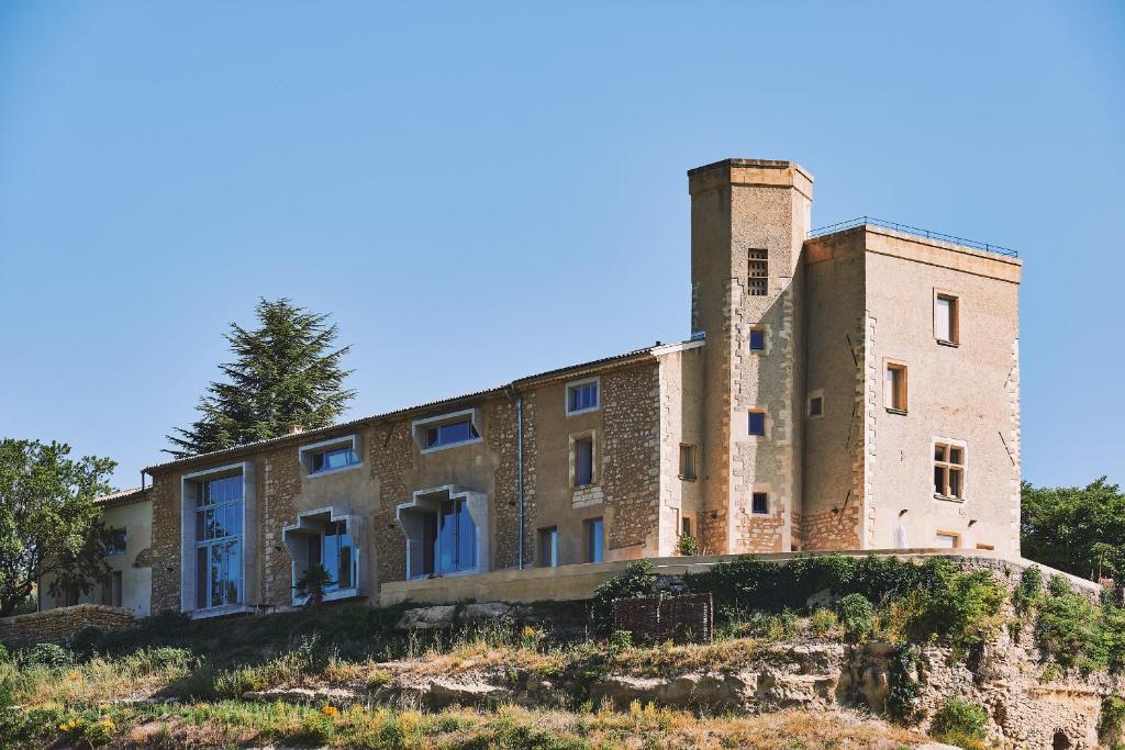 un viejo edificio de ladrillo en la cima de una colina en Domaine La Ferme HI bride, en Villelaure