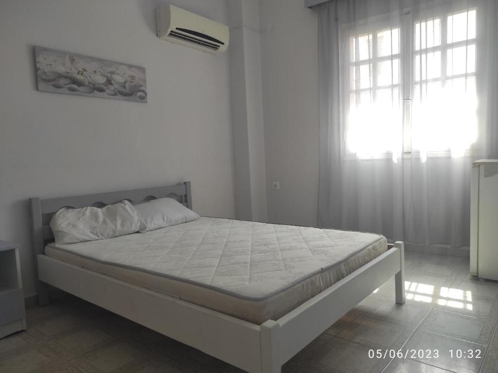 un letto in una camera bianca con finestra di ΜΚA House - λειτουργεί υπό νέα διεύθυνση 2024 a Galatas