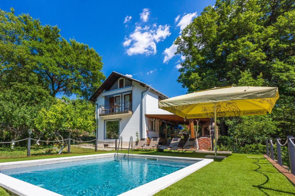 a house with a swimming pool and an umbrella at PLAVAC in Kostelj