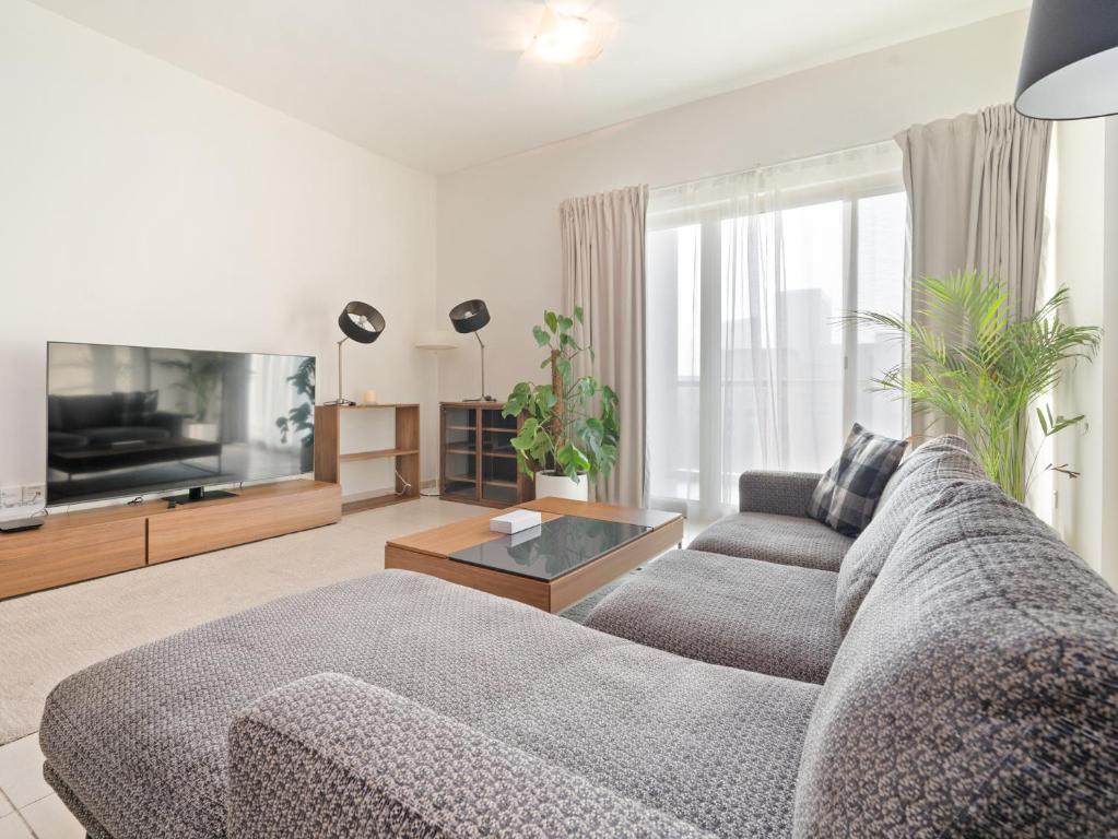 a living room with a couch and a tv at Desert Chic 1BR: An Urban Oasis In The Greens in Dubai