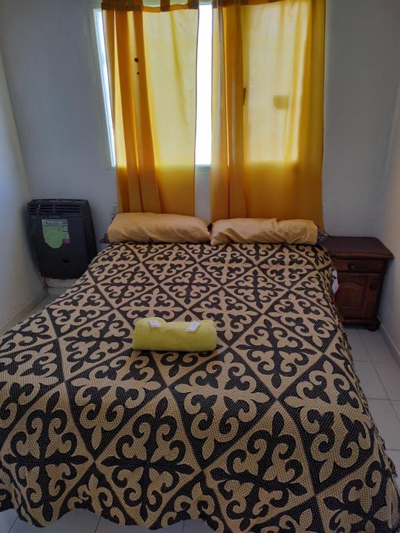 ein Bett mit einer schwarzen und weißen Bettdecke und einem Fenster in der Unterkunft comodoro sur in Comodoro Rivadavia