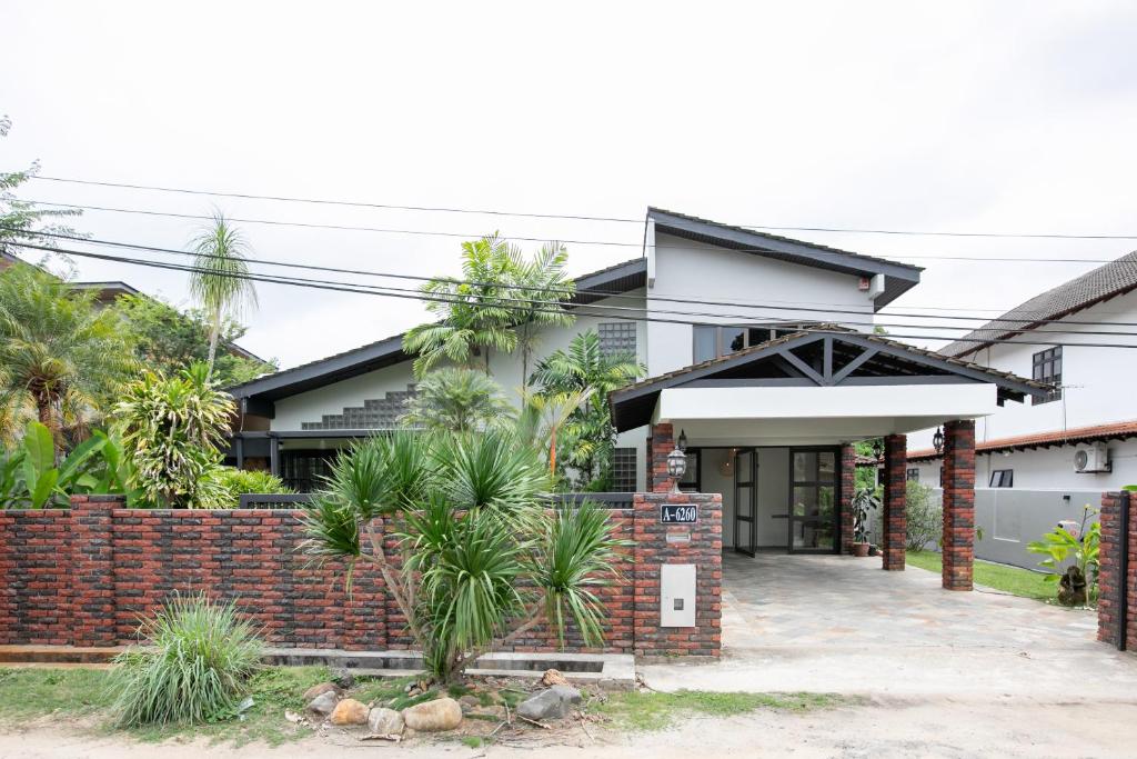 a house with a brick fence and palm trees at Kontor Mansion - 3 mins to Teluk Chempedak Beach & Private Pool in Kuantan