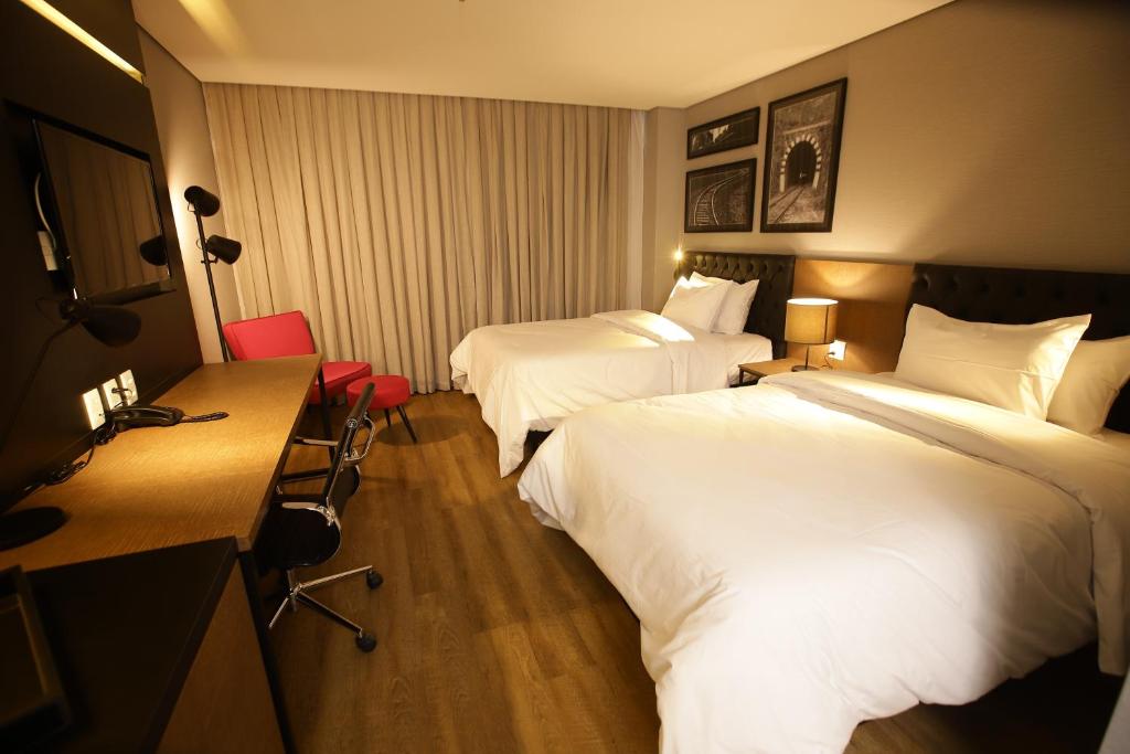 um quarto de hotel com duas camas e uma secretária em QS Marista 1202 CamasCasal em Goiânia