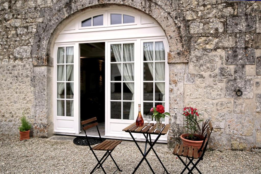 una puerta blanca con flores en una mesa frente a un edificio en La Maronniere, en Challignac