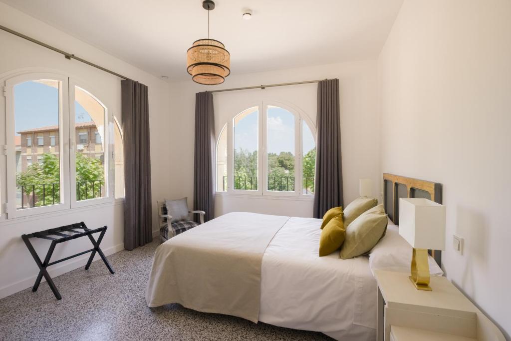 a white bedroom with a large bed and two windows at Torre Chiguita in Tarazona de Aragón