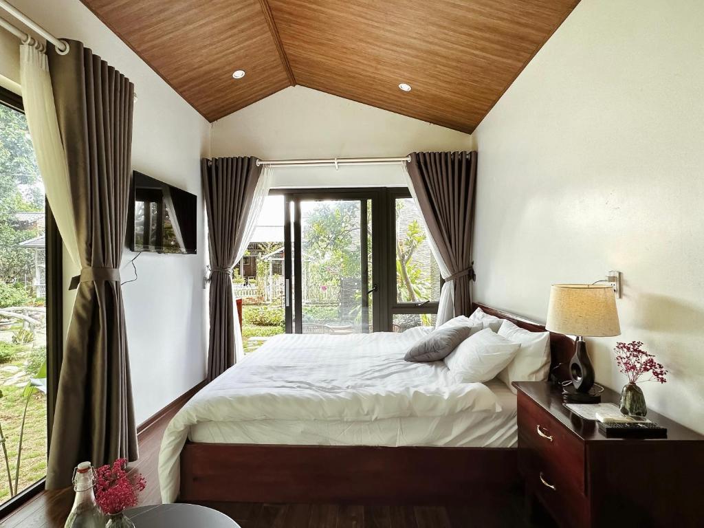 een slaapkamer met een bed en een groot raam bij Gobies Garden in Mộc Châu