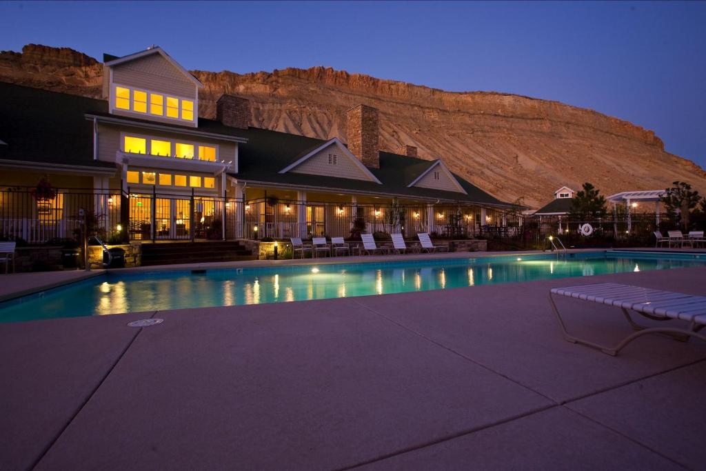 a hotel with a swimming pool in front of a mountain at Wine Country Inn in Palisade