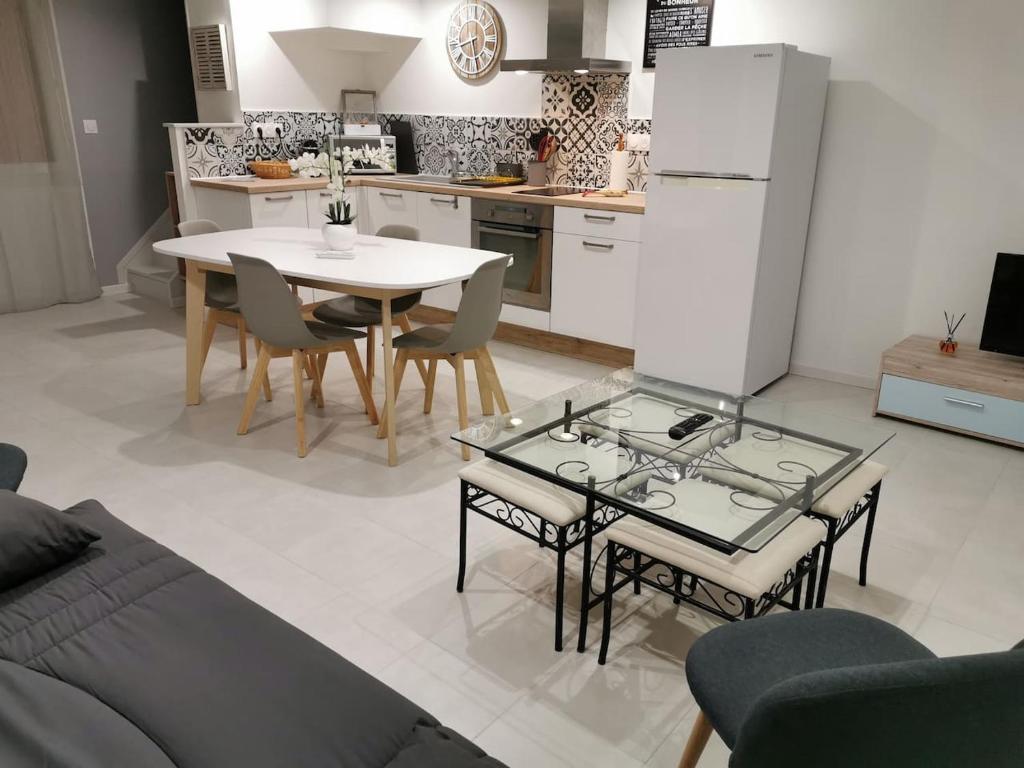 une cuisine avec une table, des chaises et un réfrigérateur dans l'établissement Jolie maison de vacances, à Saint-Laurent-de-la-Salanque