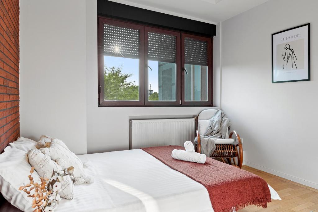 a bedroom with a bed with a chair and a window at City Heart Retreat Elegant Apartment in Bucharest