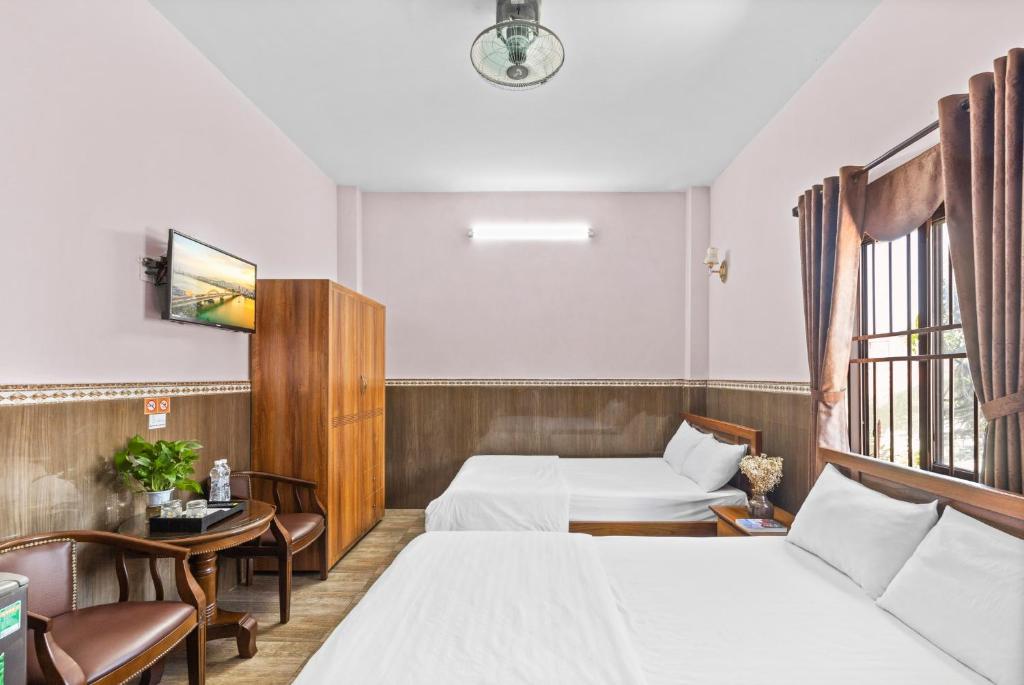 a hotel room with two beds and a table and chairs at Mộc Nhiên Hotel Da Nang in Da Nang