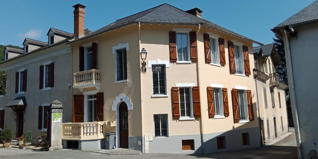 un gran edificio con persianas marrones en una calle en L'Isard, en Pierrefitte-Nestalas