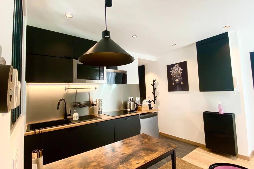 a kitchen with black cabinets and a wooden table at appartement avec vue jardin proche de Paris in Saint-Maurice
