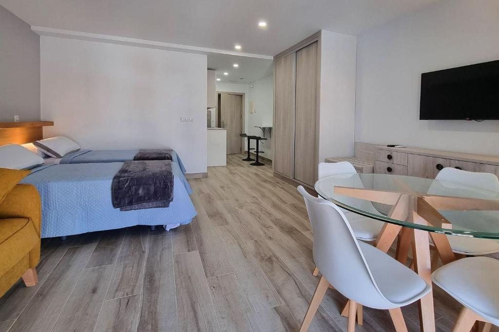 1 dormitorio con 1 cama, mesa de cristal y sillas en Apartamentos Antequera, en Antequera