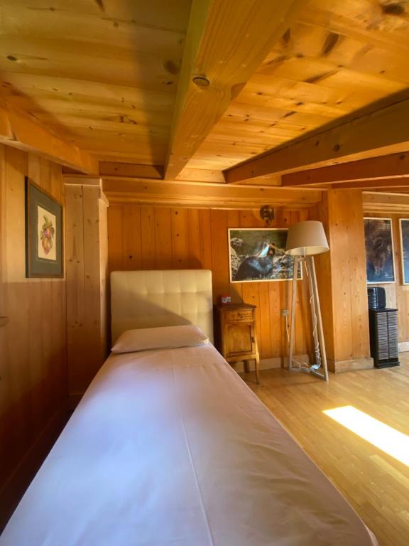 Cama grande en habitación con techo de madera en La Dimora Degli Olivi, en Galbiate