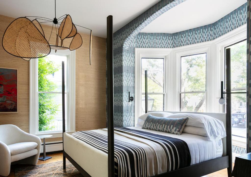 1 dormitorio con 1 cama, 1 silla y ventanas en The Swain House at 21 Broad, en Nantucket