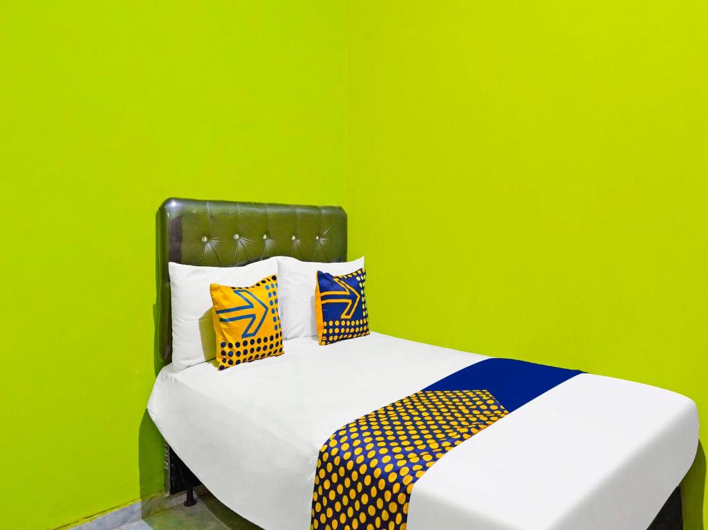 Habitación verde con cama con almohadas de colores. en SPOT ON 92786 Homestay Barokah, en Gresik