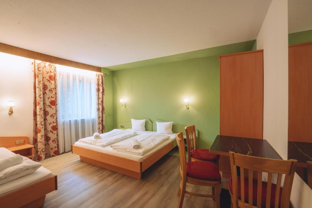 シャルニッツにあるPhiliPop-Up Hostelのベッド、テーブル、椅子が備わるホテルルームです。