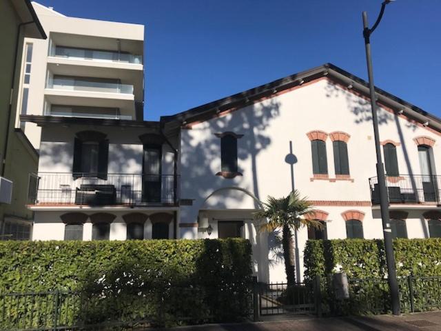 un grand bâtiment blanc avec un palmier en face dans l'établissement Casette Baradel - Agenzia Caorle, à Caorle
